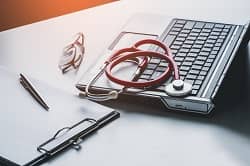 Stethoscope on laptop with pen and glasses