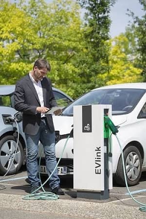 Man standing next to EVlink Parking charger, checking data on tablet